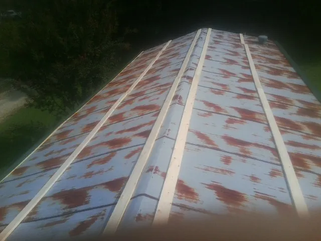 Rusted metal roof panels with new wood purlins before replacement — Storm Damage Roof Repair in Lake Lillian by Roofing Brothers