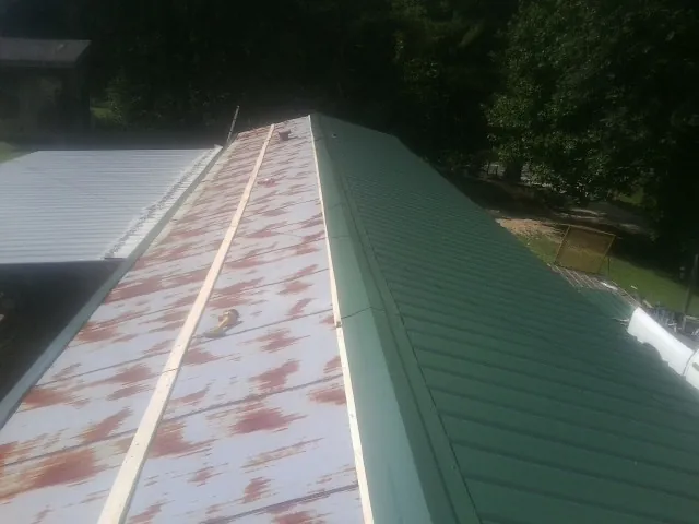 Old rusted panels beside newly installed green metal roofing — Wind Damage Roof Repair by Roofing Brothers in Lake Lillian