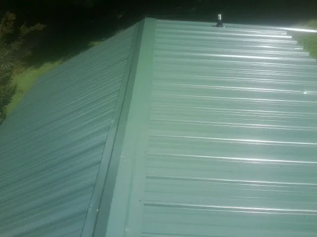 New green metal panels meeting at the ridge of a roof — Flat Roof Repair work by our crew in Lake Lillian