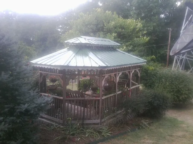 Green metal roof on a backyard gazebo surrounded by garden beds in Lake Lillian
