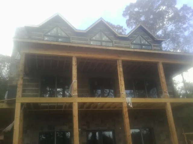 Dormers and porch framing on a large log home under construction — Roof Coating work by our crew in Lake Lillian