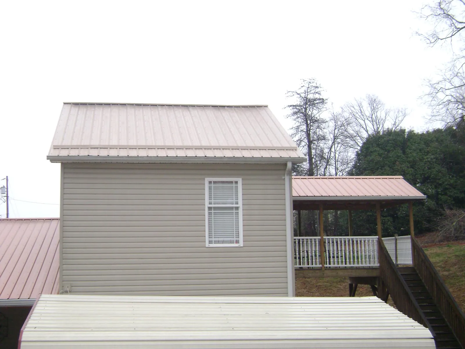Tan metal roofs on a two story addition and attached porch, from a Roof Replacement job in Lake Lillian