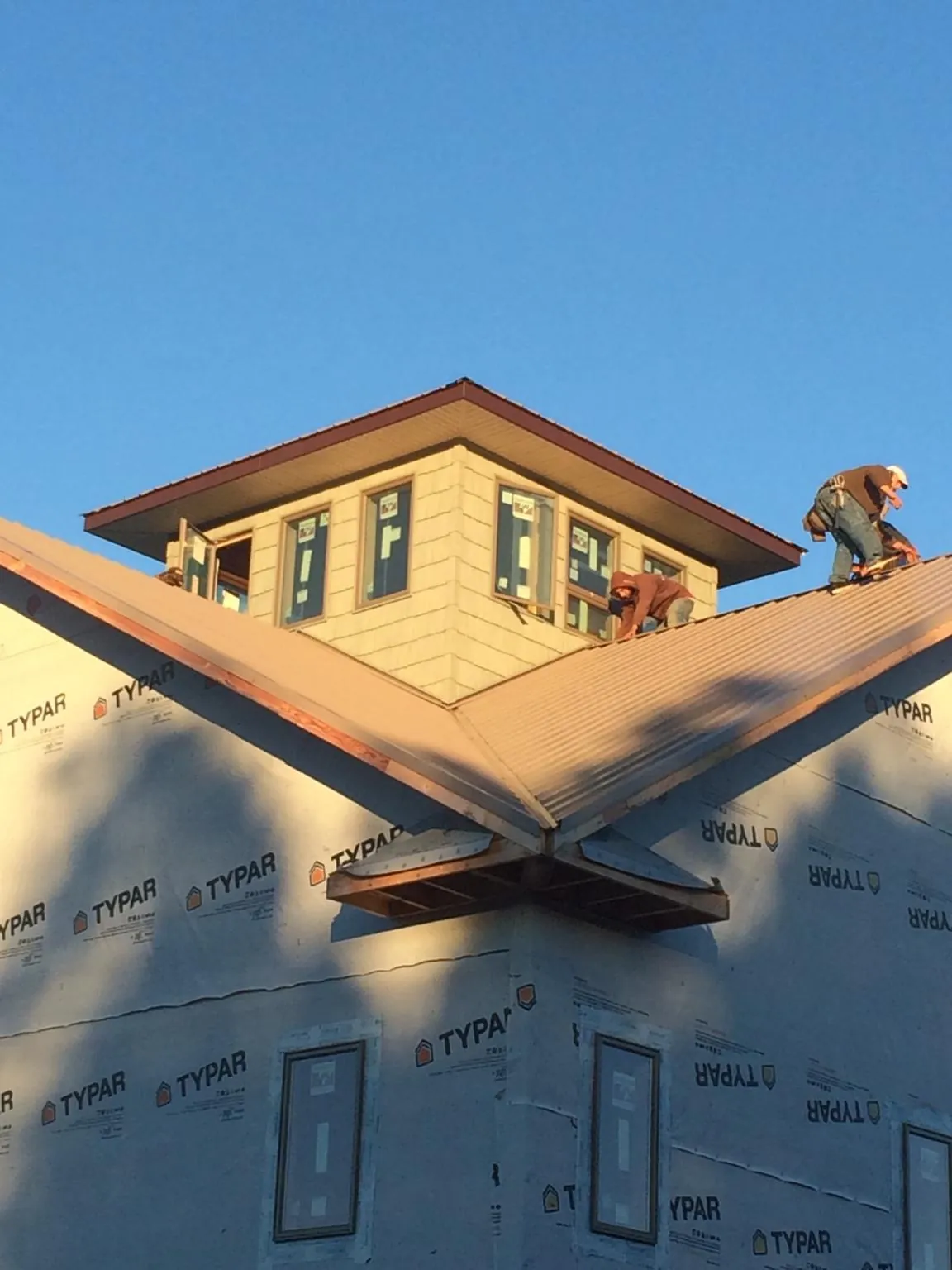 Roofers working around a rooftop cupola on a new metal roof at sunset — Roof Waterproofing in Lake Lillian by Roofing Brothers